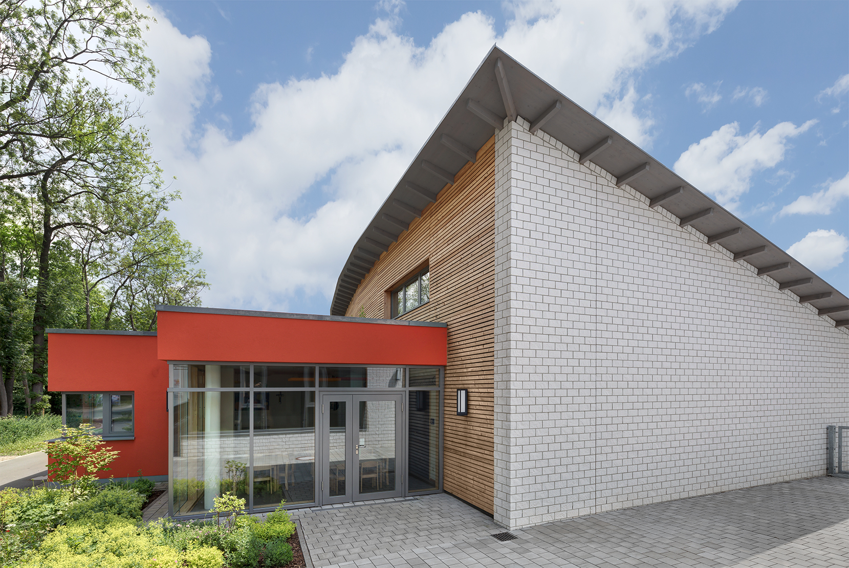 Während der eingeschossige Nordteil des Kita-Baus verputzt ist, bekam der zweigeschossige Trakt eine Fassadenbekleidung aus weißen Kalksandsteinverblendern und Lärchenholz.